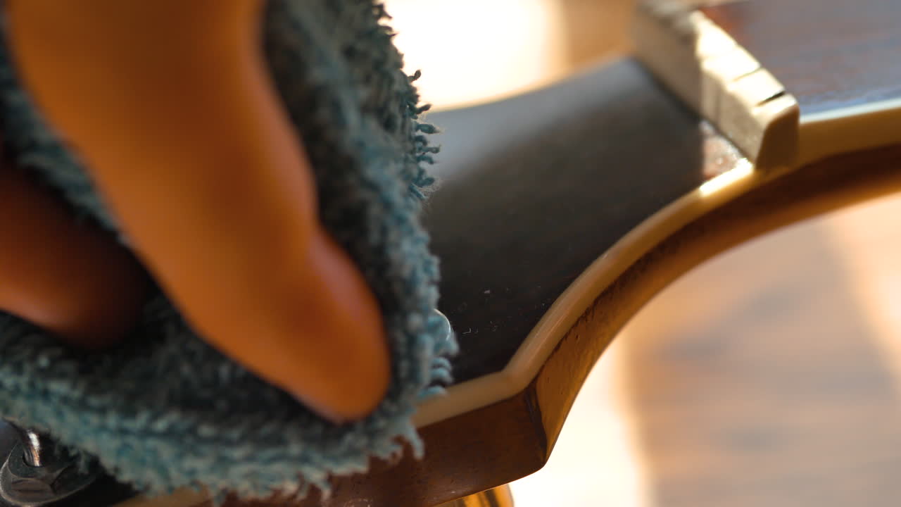 músico limpiando y engrasando el cuello y el cuerpo de una guitarra acústica