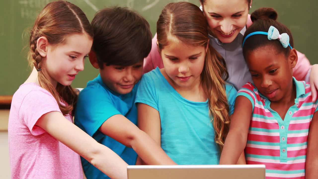 maestro y alumnos mirando la computadora portátil