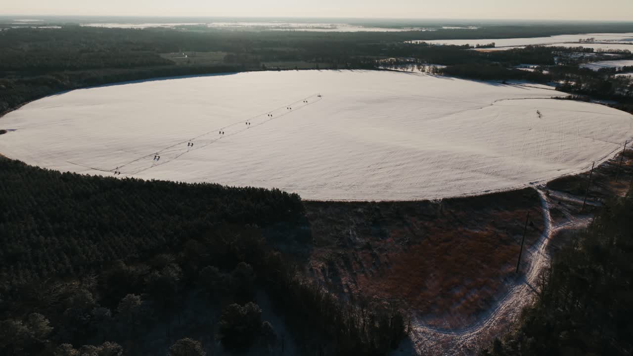A breathtaking pan-up drone reveal of a large circular field coated in snow with an irrigation pivot at its center, filmed during South Georgia's rare snowfall.