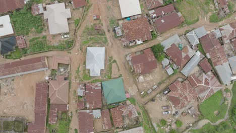 Aerial---Small-town-with-rusty-roofs-and-dirt-road,-top-down-reverse