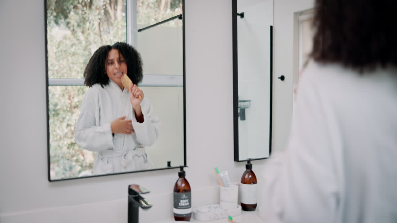 Woman singing into hairbrush in bathroom mirror