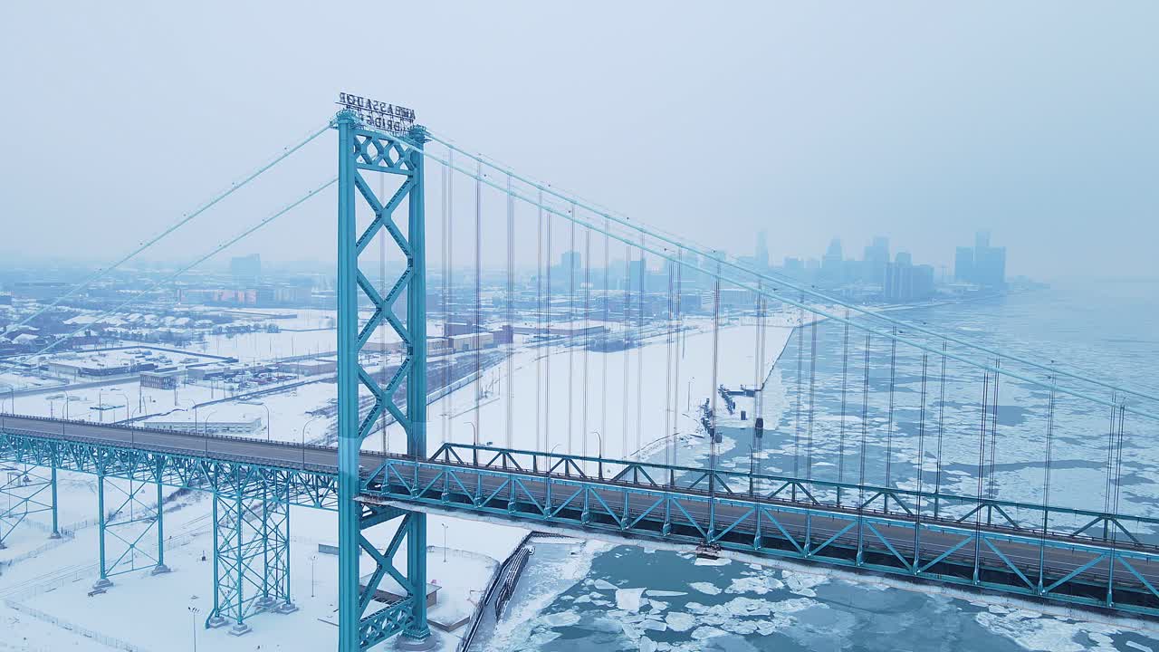 Ambassador Bridge rises above icy river with downtown Detroit skyline in distance, USA