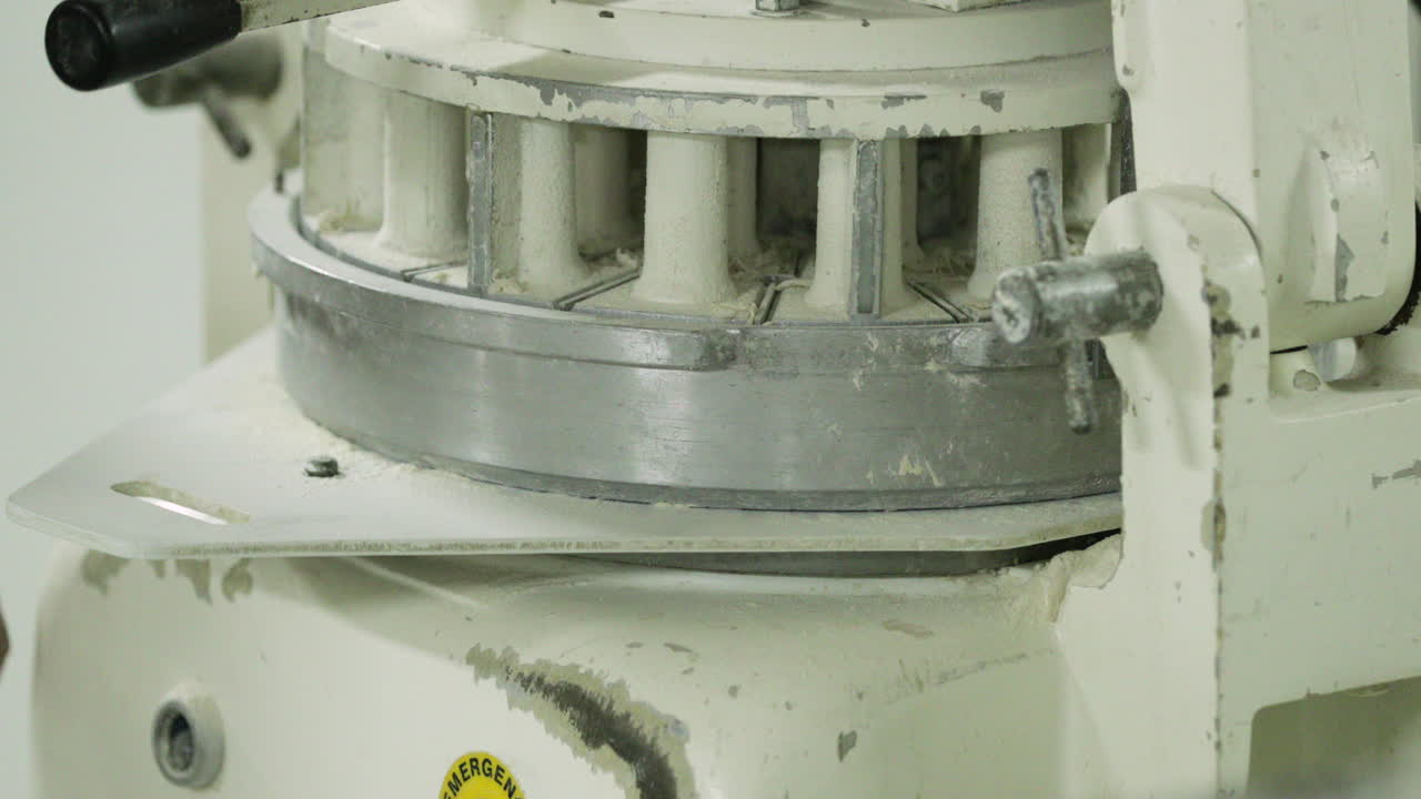 тесторазделочная машина в пекарне - пекарь кладет тесто на делитель и режущую машину для нарезки на одинаковый вес