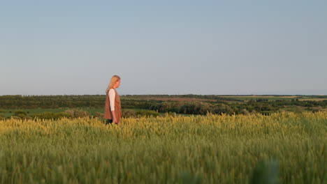 a woman walks through a field of wheat against the backdrop of a picturesque rural landscape