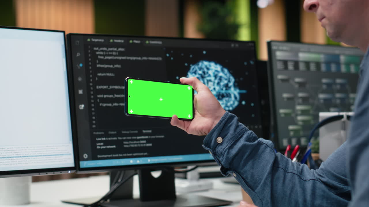 Developer Holding Smartphone with Green Screen in Modern Office