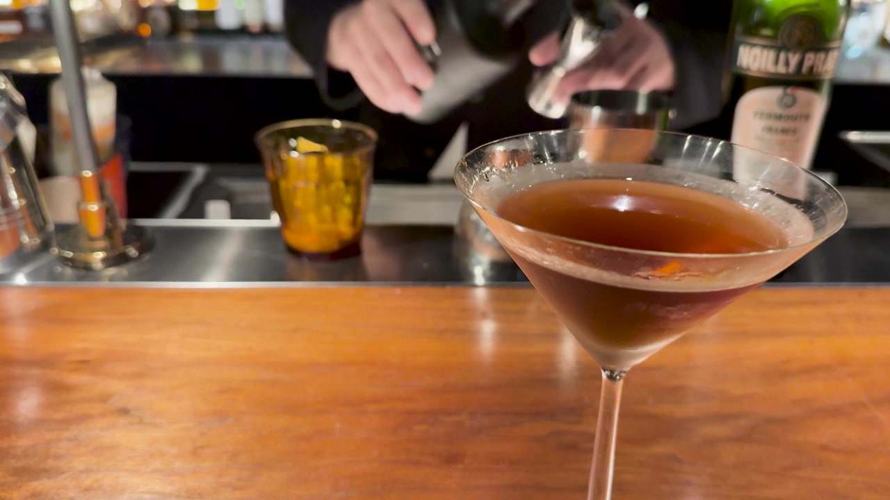 Barman che prepara un cocktail al bancone di un bar
