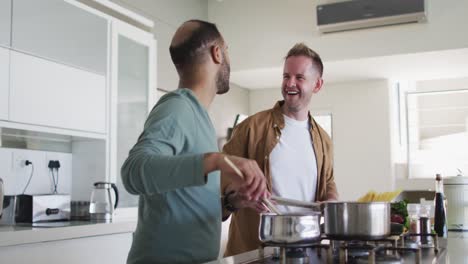 Multi-ethnic-gay-male-couple-preparing-food-in-kitchen