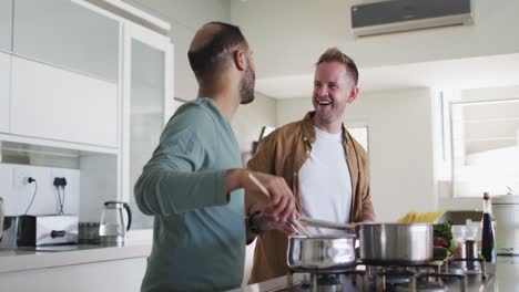 pareja de hombres homosexuales multiétnicos preparando comida en la cocina