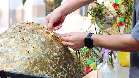 applying gold leaf to a sacred stone for blessings