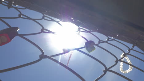 padlocks and ribbons on iron mesh on sky and sun background