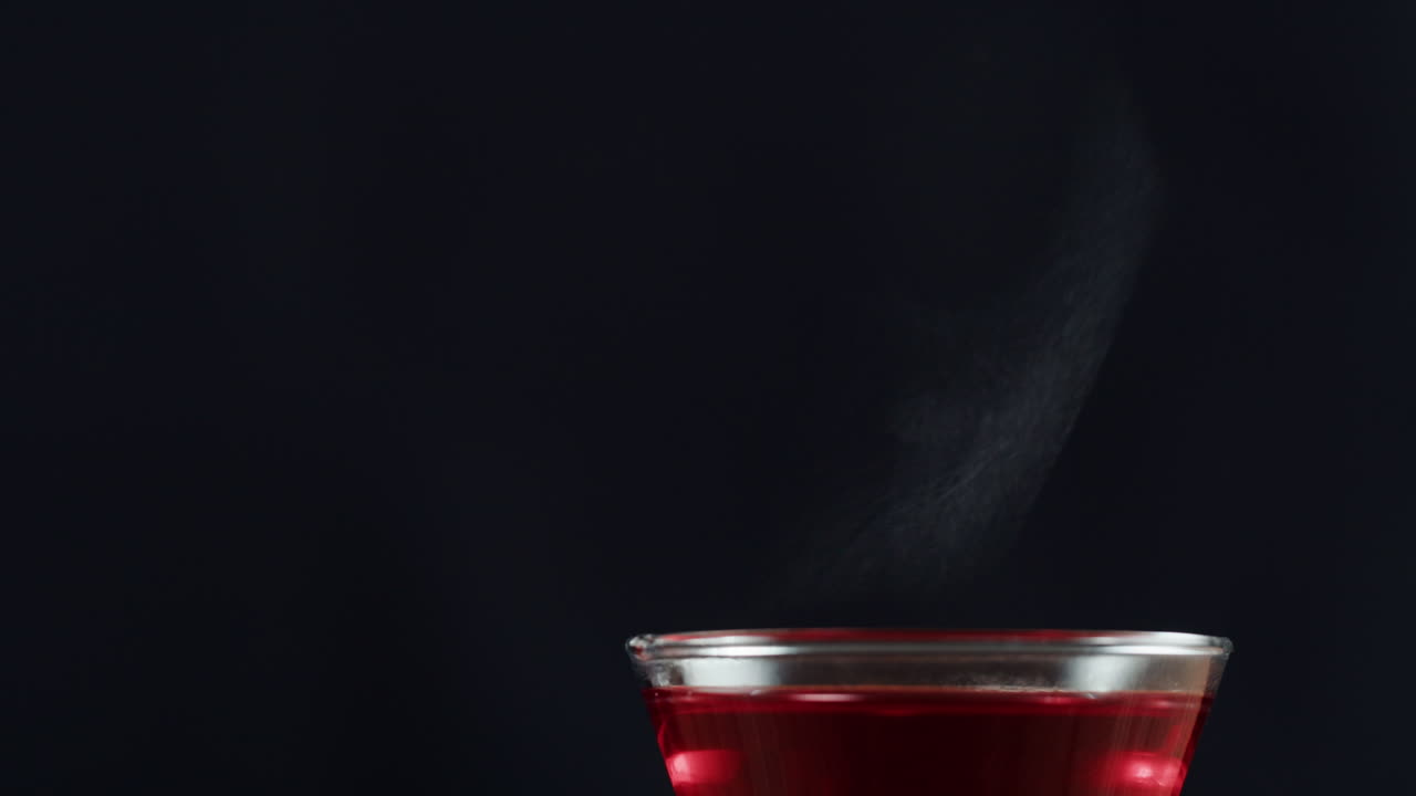 Hot Red Drink in Glass with Steam on Dark Background