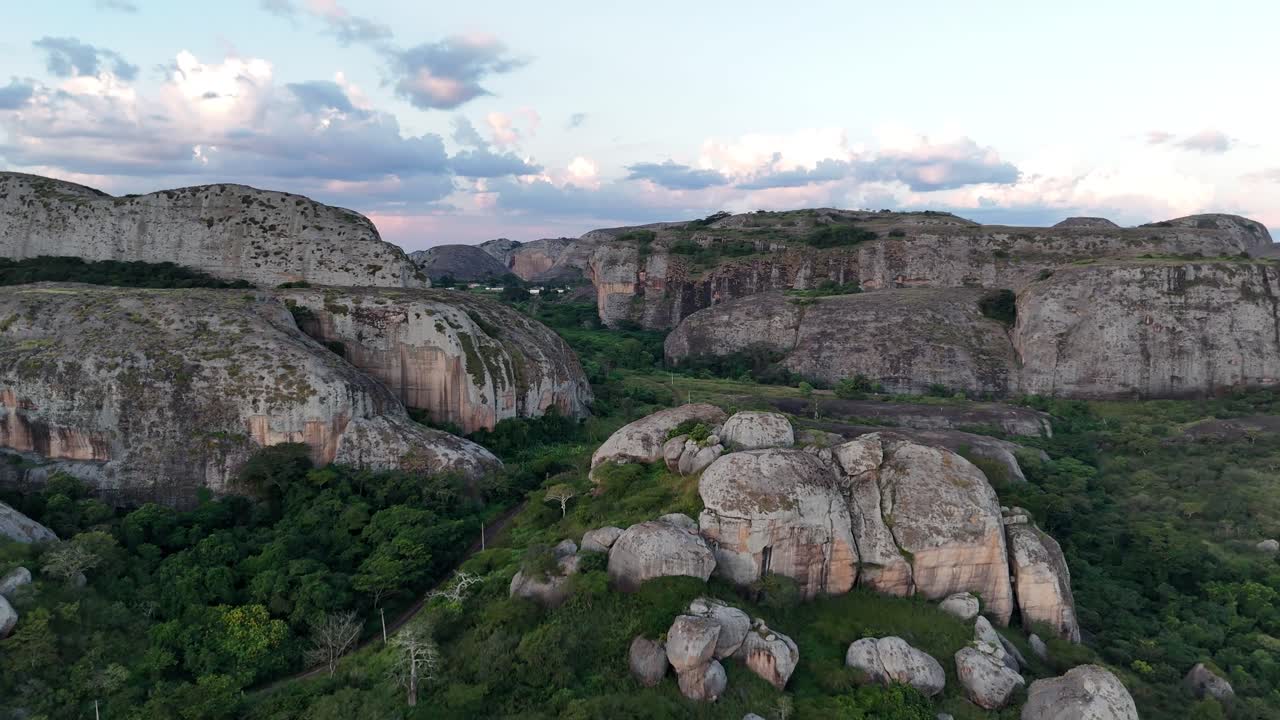 Spettacolare volo di drone sopra gli antichi giganti di pietra dell'Angola, che cattura il contrasto drammatico tra le rocce scure e le vivaci pianure africane.