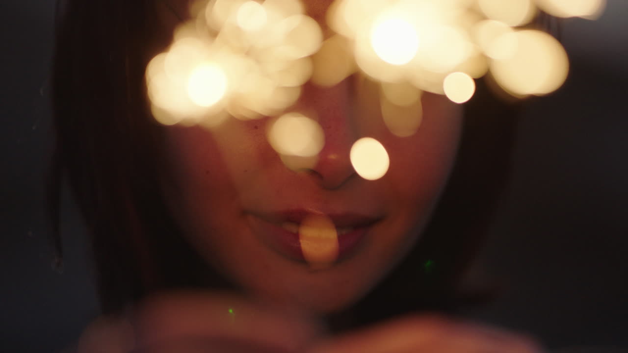 섣달 그믐 날을 축하하는 폭죽을 닫은 행복한 아시아 여성은 해질녘 해변에서 독립 기념일 축하를 즐기며 웃고 있습니다.