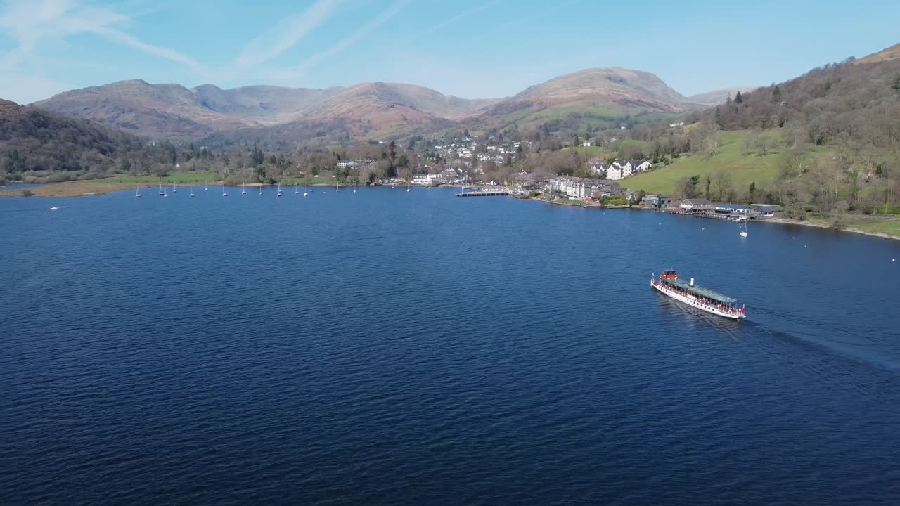 Drone following boat heading towards Ambleside Town on Lake Windermere on sunny day - Lake District, England