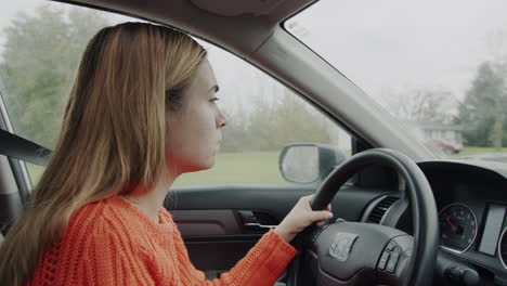 A-focused-young-woman-driving-a-car-drives-through-an-American-suburb.