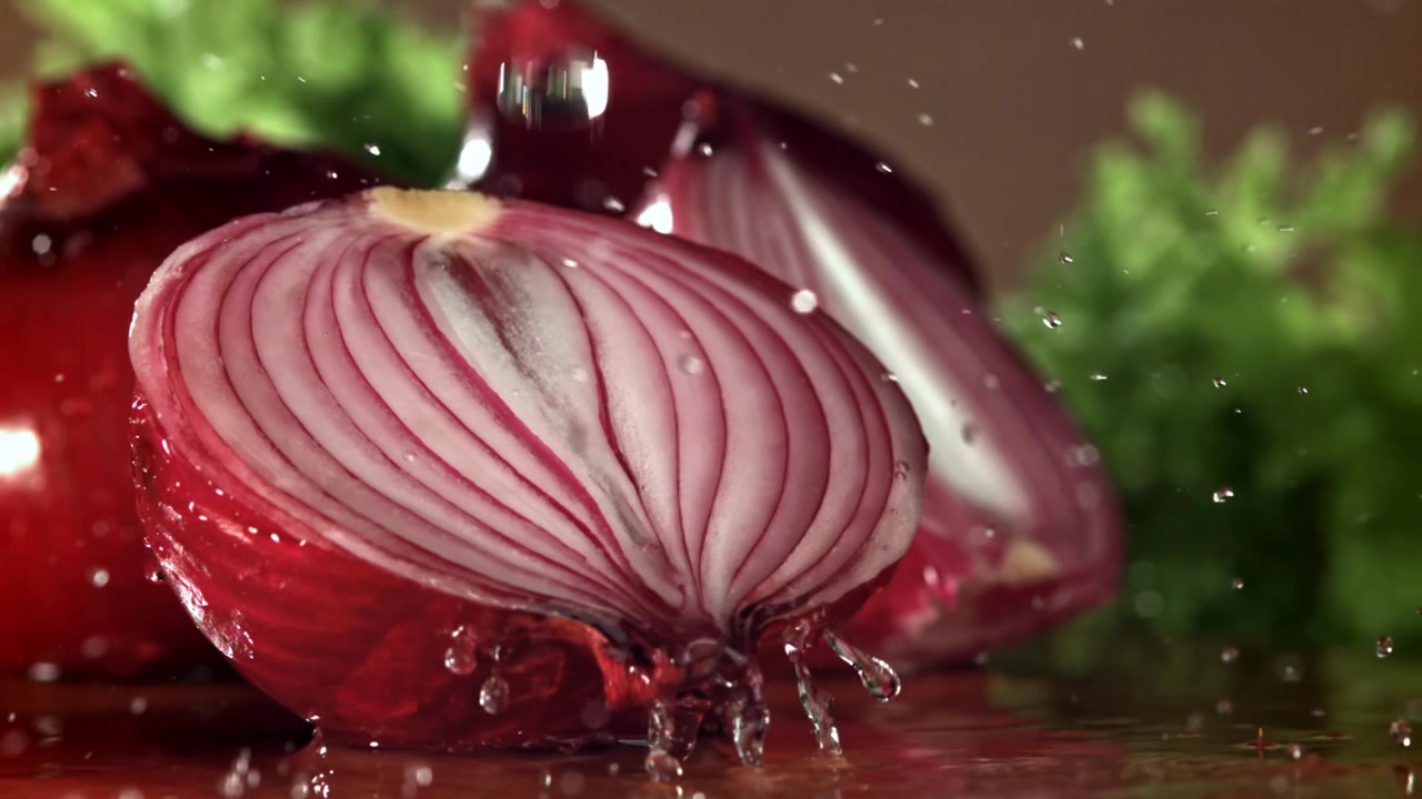 Close-up of Water Splashing on a Fresh Red Onion Half