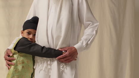 fotografía de estudio de un joven sikh con un turbante de nudos superiores abrazando a su abuelo contra un fondo plano 1