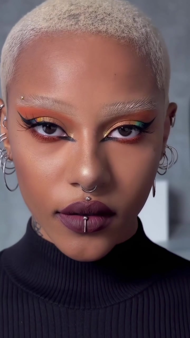 Nærbillede af en kvinde med farverig makeup og piercinger