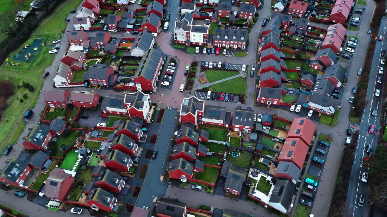 Flygbilder tagna med drönare över ett lokalt engelskt villaområde i södra England under blå timmen i solnedgången. Med livligt trafikerade vägar och en lugn atmosfär med trädgårdar, träd och en damm