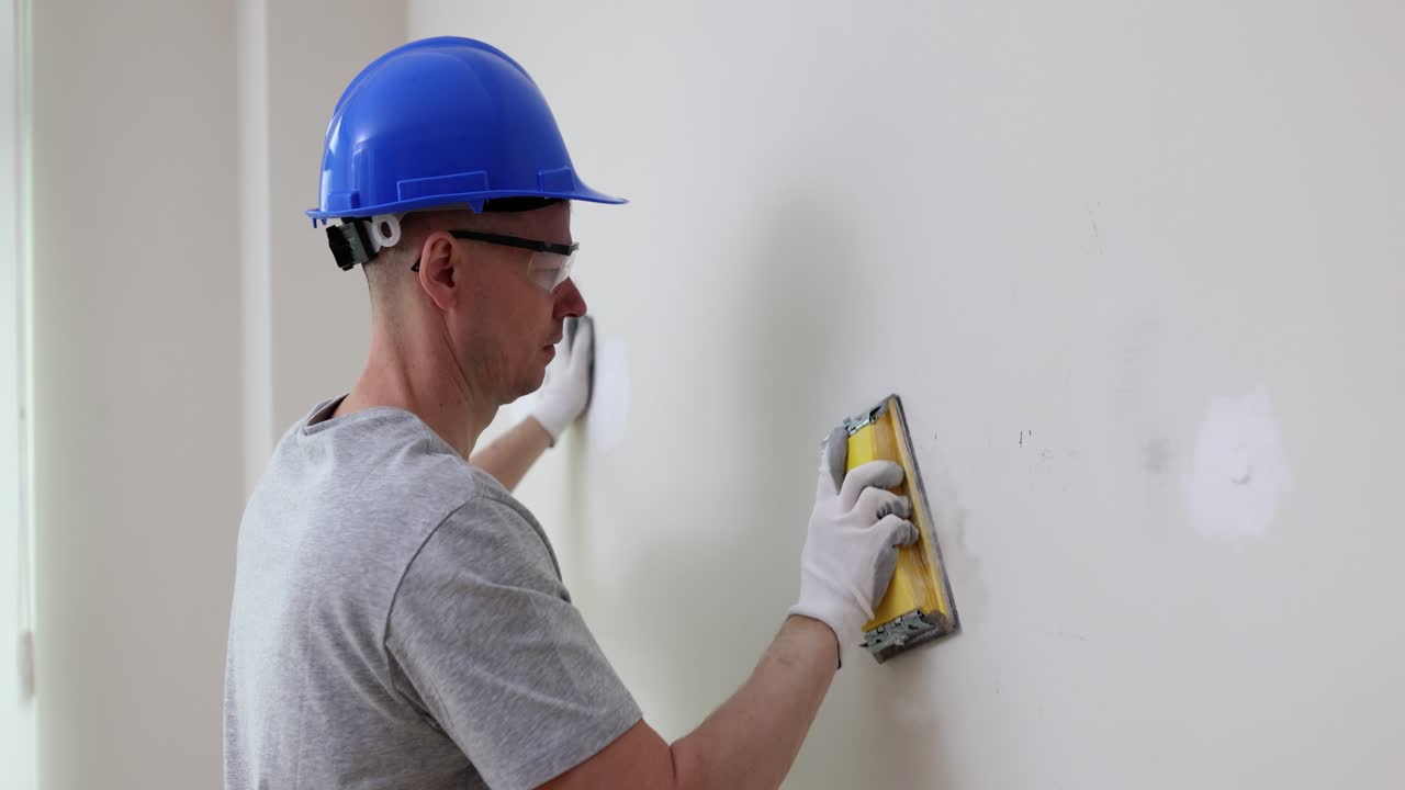 Construction worker sanding wall