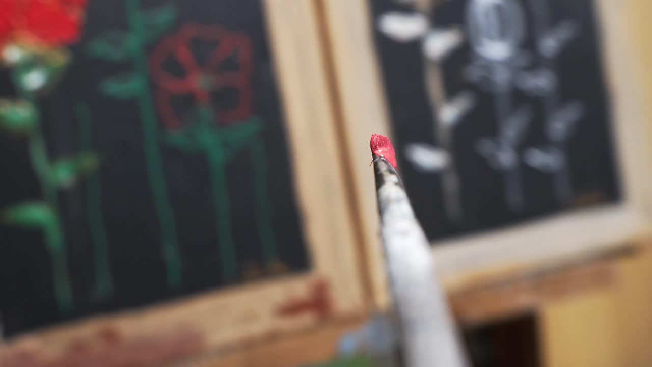 First person view of holding a painters brush and dabbing it in the red paint of the colorboard.