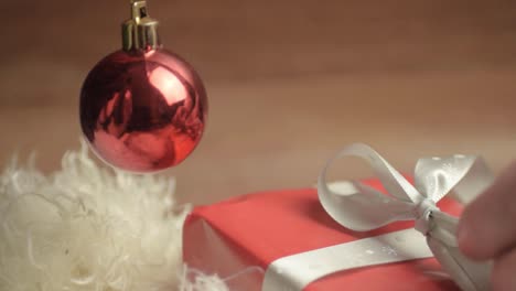 desenvolviendo un regalo de navidad envuelto con papel rojo y lazo con adorno rojo