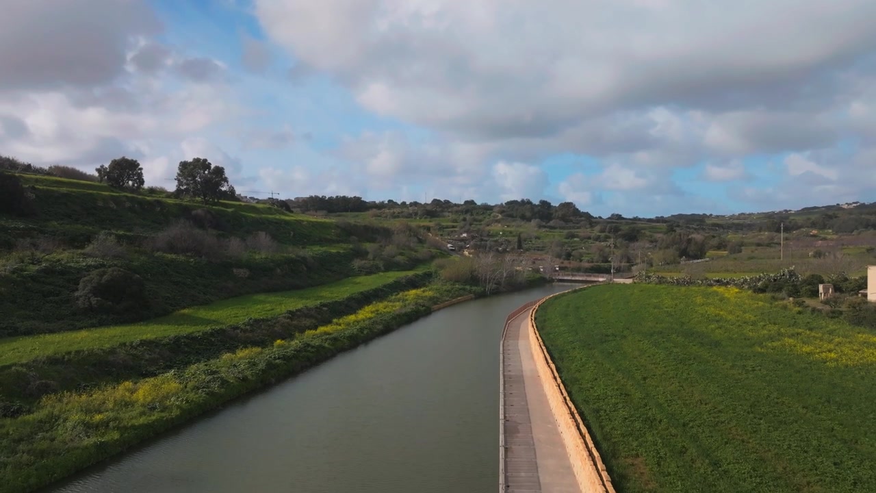 Vista aerea di un fiume calmo che scorre attraverso un paesaggio verde sotto un cielo nuvoloso.