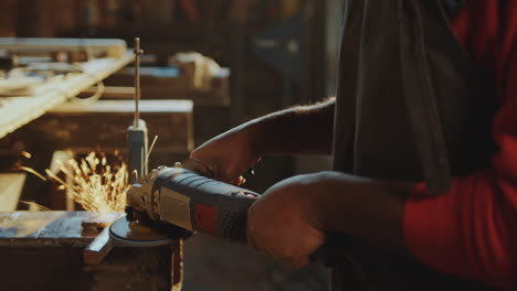 african american blacksmith grinding steel billet in workshop