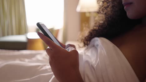 woman using smartphone in bed in a hotel room