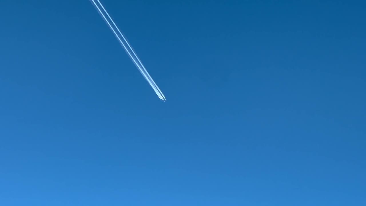 푸른 하늘을 가로지르는 거대한 군사 4 엔진 항공기의 콘트레일, 벨로를 날아가는 비행기에서