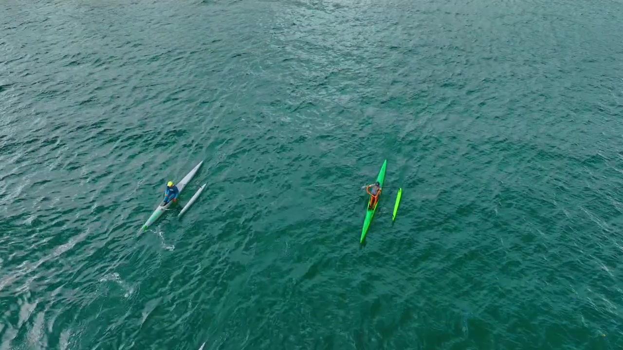 Four kayakers rowing by the blue waterscape. Practicing canoeing in a group. Top view.