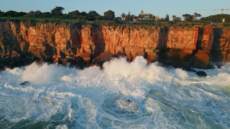 el agua de mar tormentosa salpicando chocando contra la orilla rocosa aérea. olas de océano espumosas
