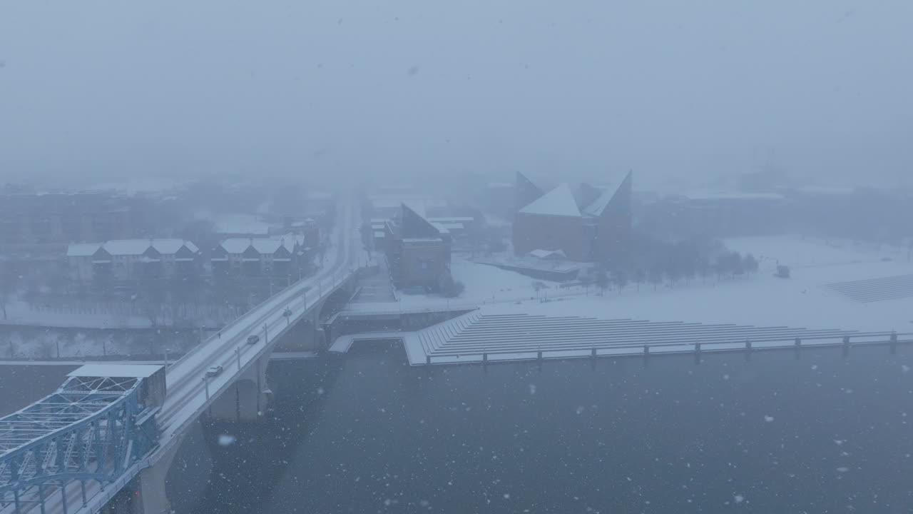 Aerial footage during a snowstorm flying over the Tennessee River with Market Street Bridge and the Tennessee River in the shot.