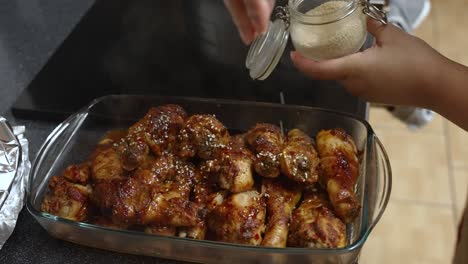 dried seeds being sprinkled over freshly cooked chicken meat