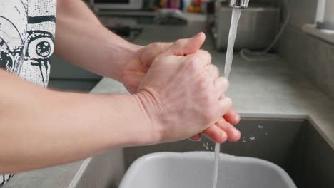 A-man-washing-his-hands-at-the-kitchen-sink