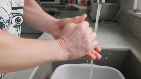 Un-Hombre-Lavándose-Las-Manos-En-El-Fregadero-De-La-Cocina