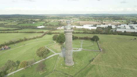 Historic-Spire-of-Lloyd-in-Kells,-Ireland,-surrounded-by-green-fields-and-partly-cloudy-skies,-aerial-view