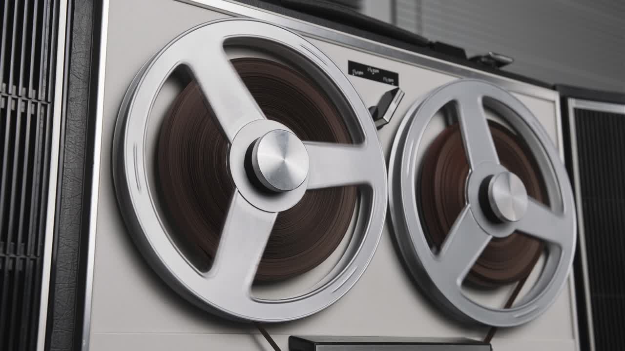 릴 테이프 레코더를 재생합니다. 릴 회전 빈티지 음악 플레이어 가까이. 레트로 테이프. 회전 릴 금속 색상. 위에서 볼 수 있습니다. 인기있는 디스코 트렌드 60s, 70s, 80s, 90s.