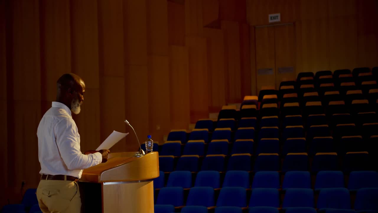 Senior African American businessman practicing speech in empty auditorium 4k