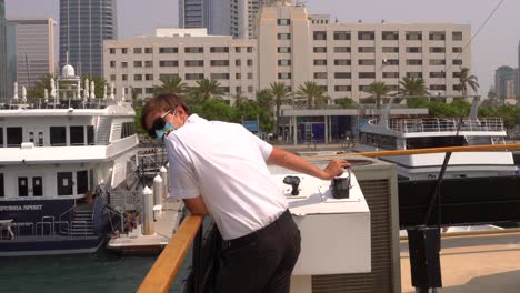 ship captain master in uniform steering the vessel into its dock in the city of san diego, california on a sunny day