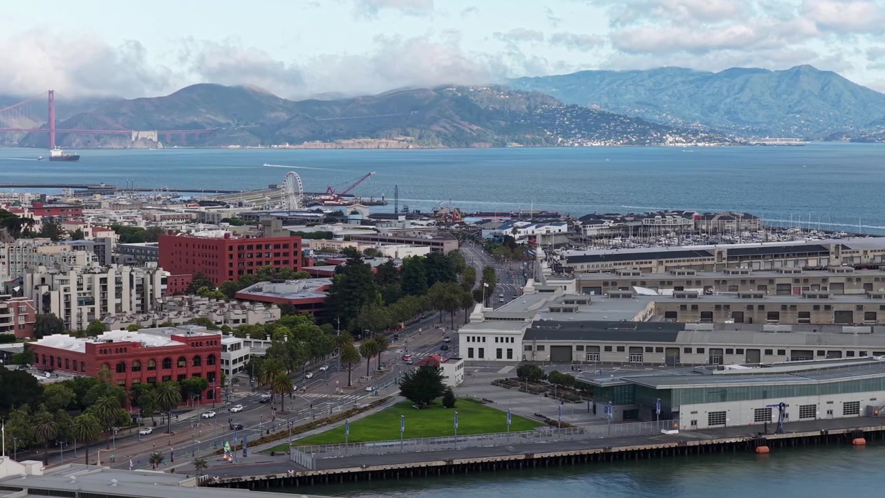 Vista mattutina del lungomare dell'Embarcadero con il Golden Gate Bridge in lontananza a San Francisco, California. Ripresa aerea laterale.