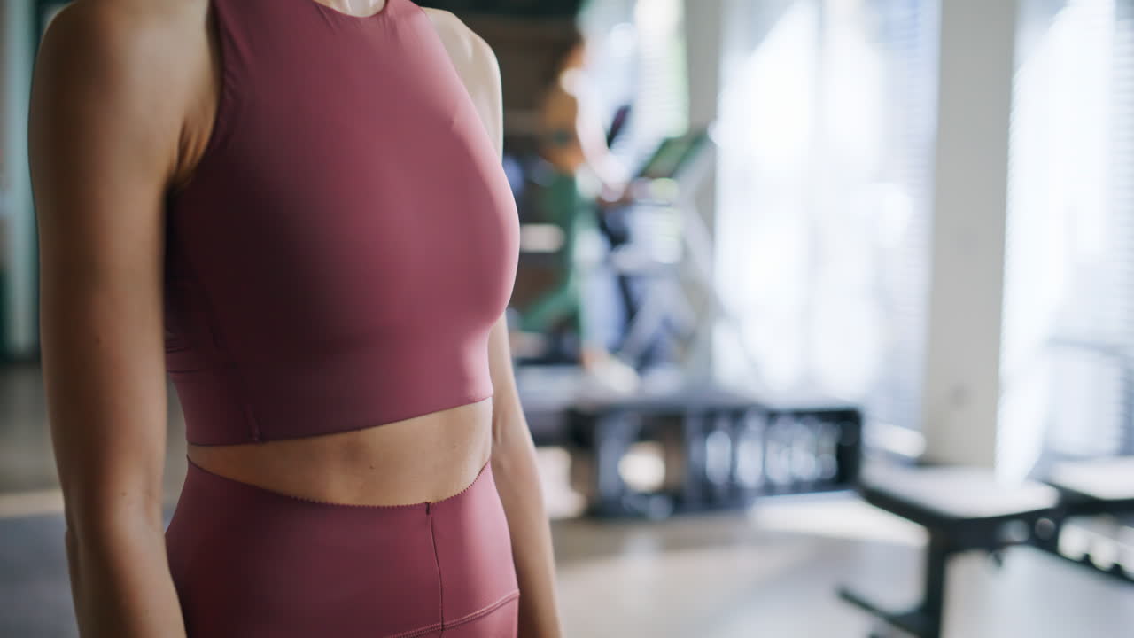 Woman checking fitness tracking app on smartwatch standing sunny sport club