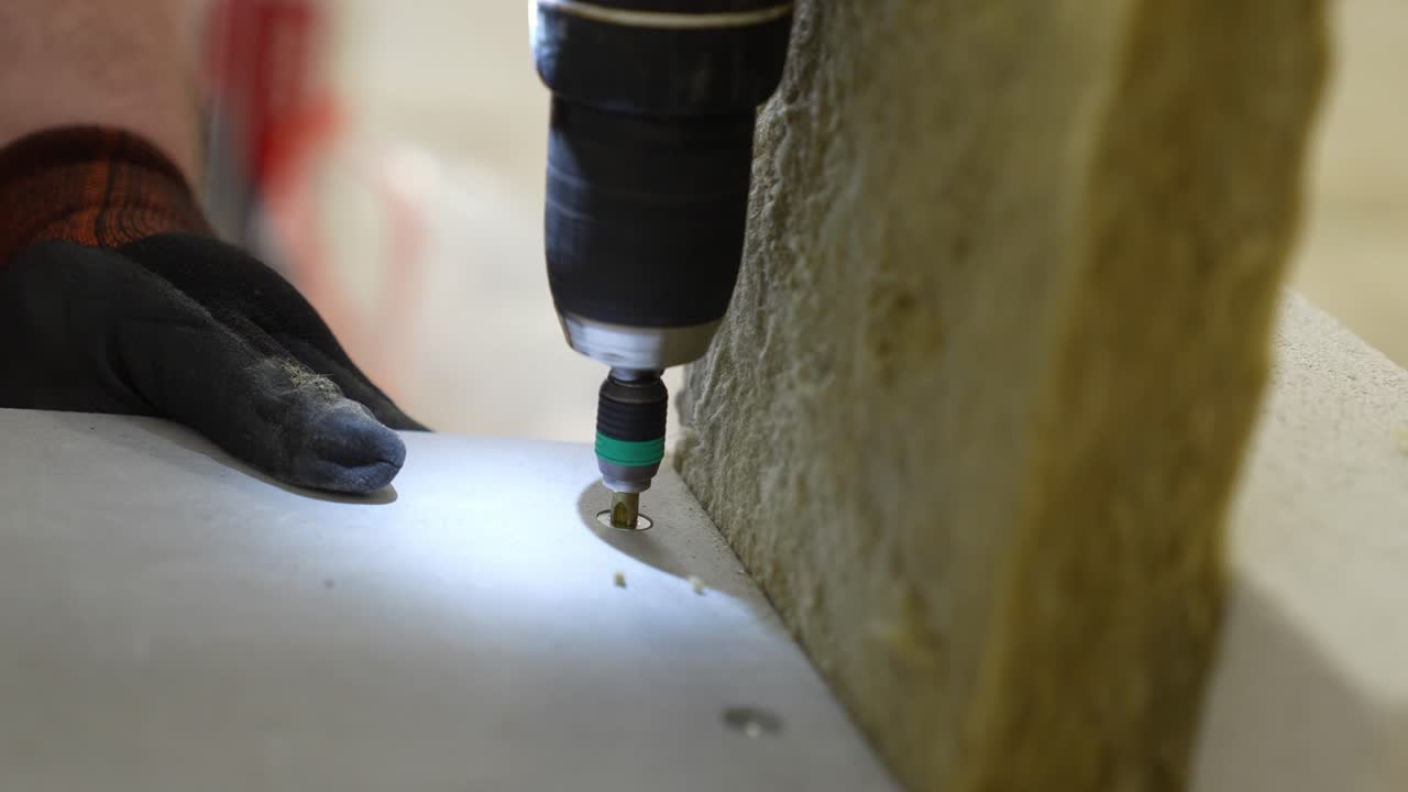 Fissaggio a vite di precisione per piastre tagliafuoco industriali. L'assemblaggio con trapano avvitatore a batteria professionale fissa pannelli protettivi su lana minerale e mattoni in muratura per una sicurezza strutturale certificata
