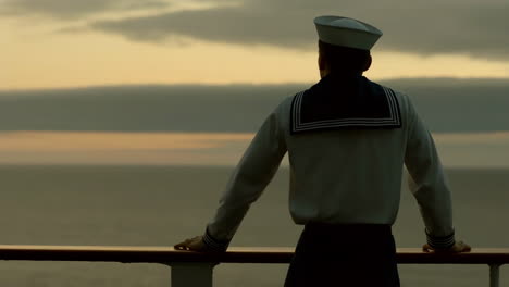 sailor gazing at the ocean at sunset