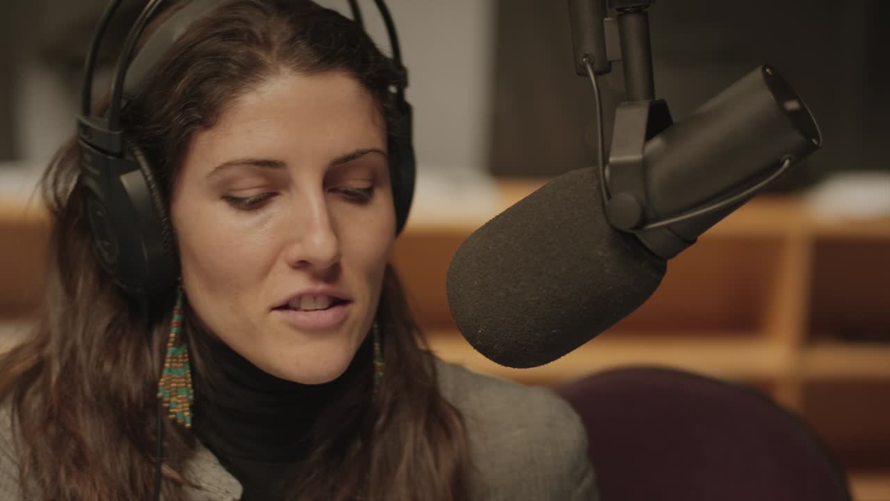 Primo piano di una donna che parla in uno studio radiofonico.