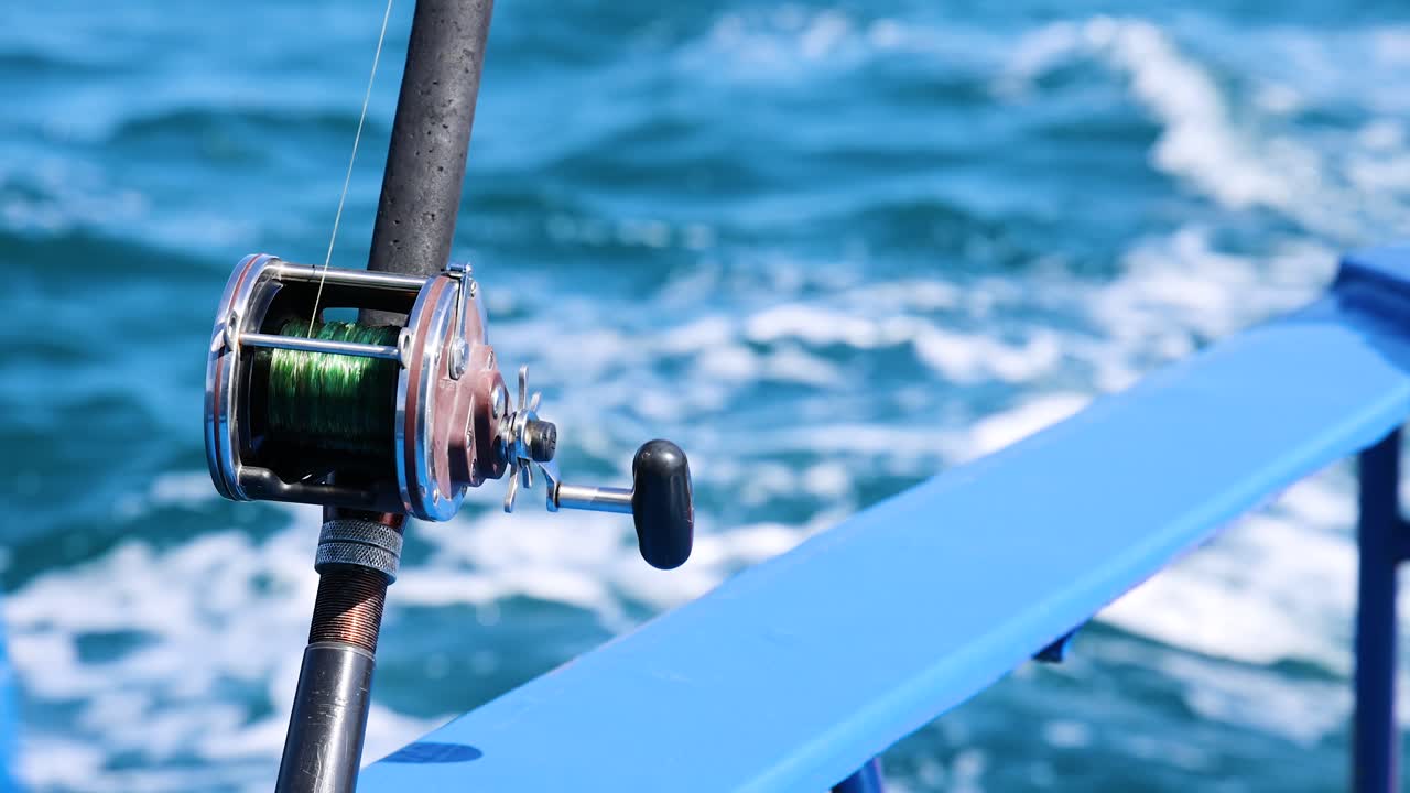 Una canna da pesca su una barca a Phuket, Thailandia, cattura l'essenza di una serena battuta di pesca con vivaci onde oceaniche.