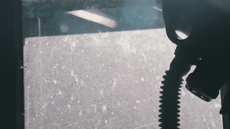 silhouette of a gas mask on a window against the sun