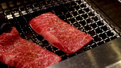 marbled beef slices sizzling on a metal grill, showcasing texture and cooking process.