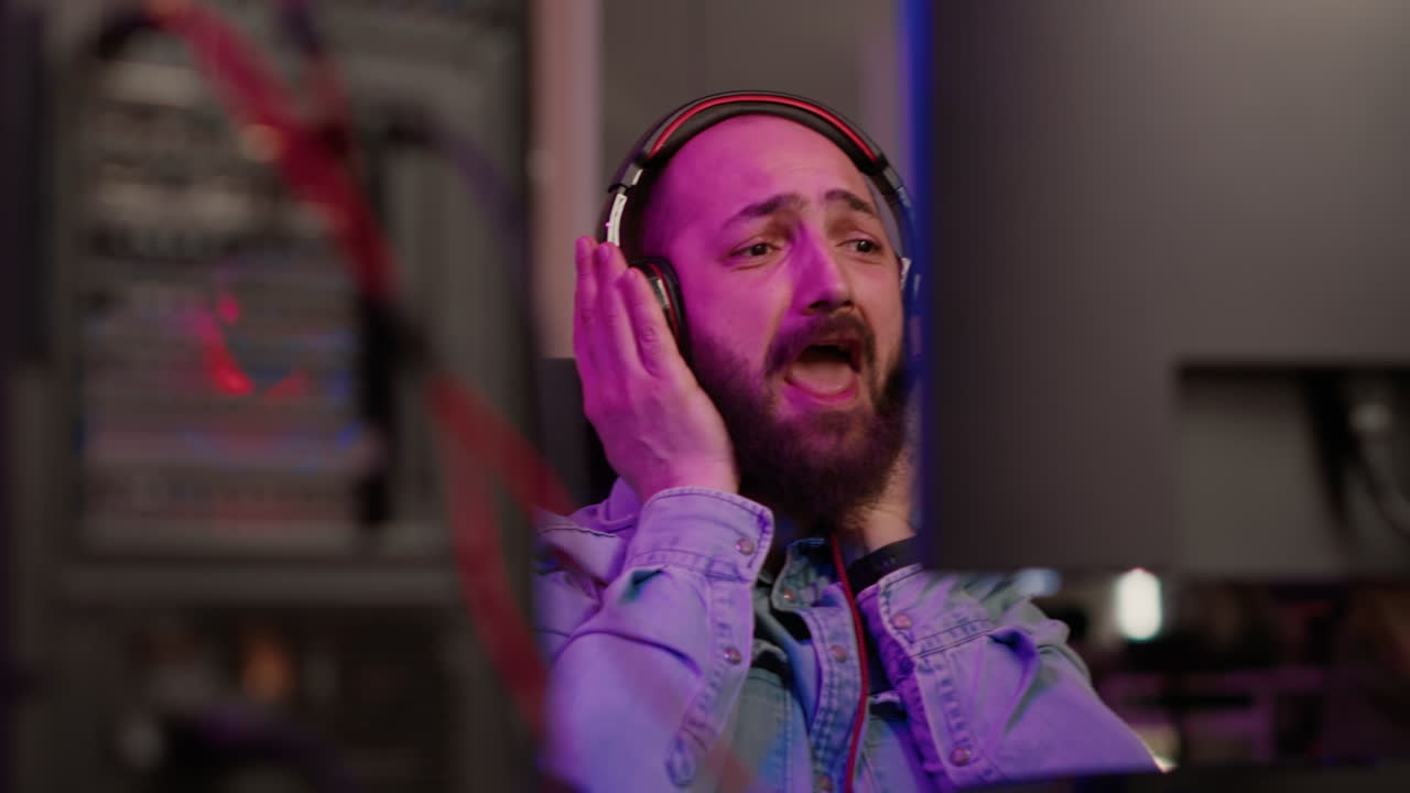 Handheld shot of gamer with headset streaming gameplay shouting after winning online multiplayer game