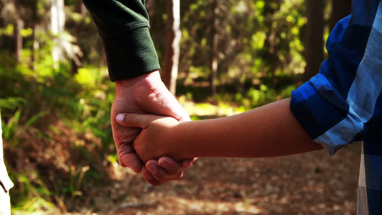 padre sosteniendo a sus hijos de la mano en el parque